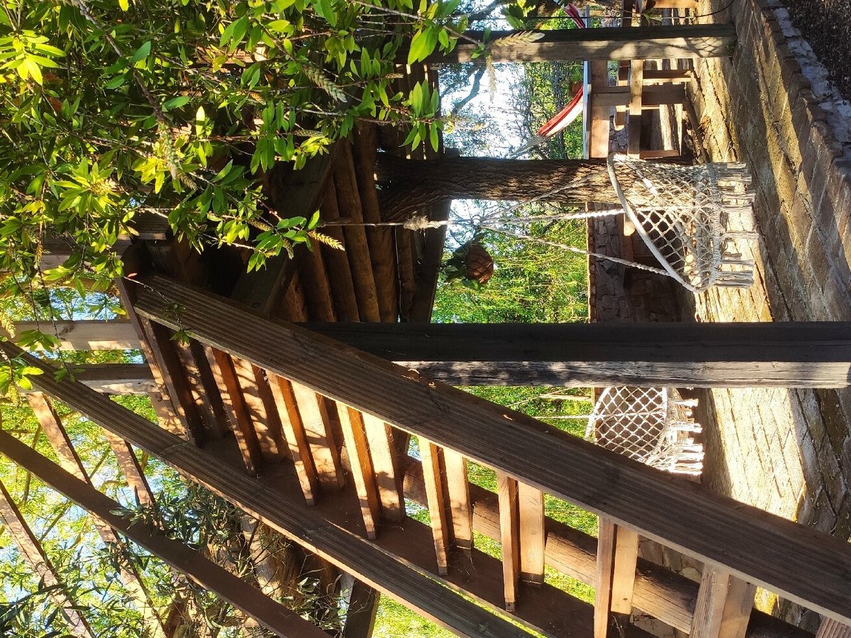 Zona de estar sob pérgola de madeira no Monte da Floresta, com vista para o jardim.